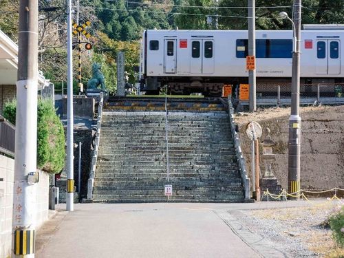 参道の途中に電車が通る珍百景。境内の陶器の鳥居や狛犬と合わせて親しまれています。[陶山神社]
