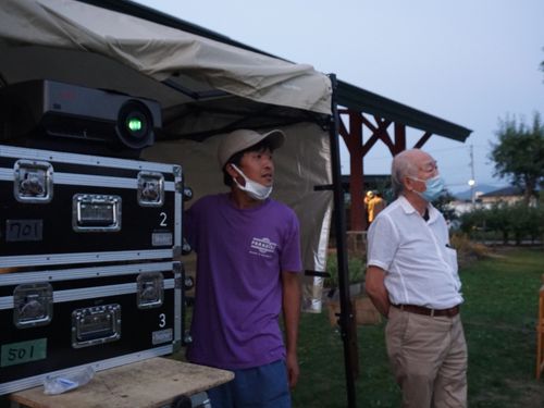 広い公園で屋外上映会を開催中、プロの顔を覗かせる安倍さん（写真左）
