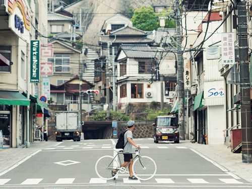 市街地。駅から続く商店街、線路の向こうに続く坂道。