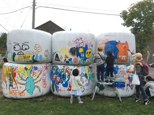 マルシェイベントの1コーナーでは、牧草ロールにみんなでペイント。協力隊OGのアーティストがサポート