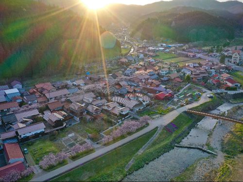 早朝、春のがいせん桜通りと村中心部。春は桜、夏は新緑、秋は紅葉、冬は雪景色と、四季豊かな景色がのぞめます。(ドローンでの撮影風景、提供：Ojiro Sky.)