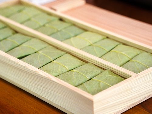 包み終わったものを木の箱に入れて、ぎゅっと押すと完成します。（だけど、包むのも難しいし、箱に入れている途中に広がったりもして難しい…！）