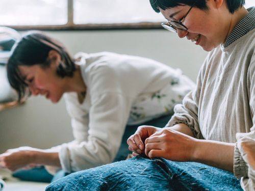 就業先で同僚と繕い物をする様子