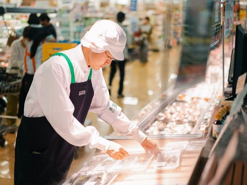 生鮮食品売り場でパックをきれいに並べる中村さん。