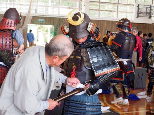 武者行列に向けて地域みんなで甲冑着付け