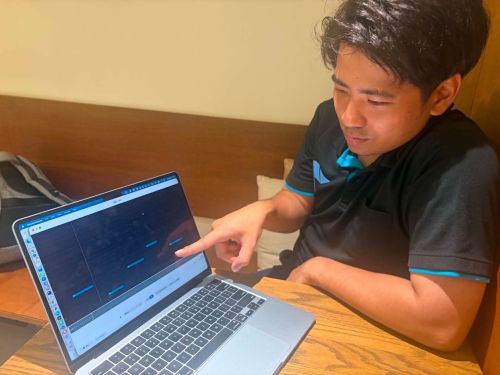 自身が三線を練習ために開発した「三線のカラオケシステム」を説明する鳩間さん