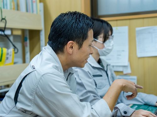 事務所で、松本さんと社員が打ち合わせ