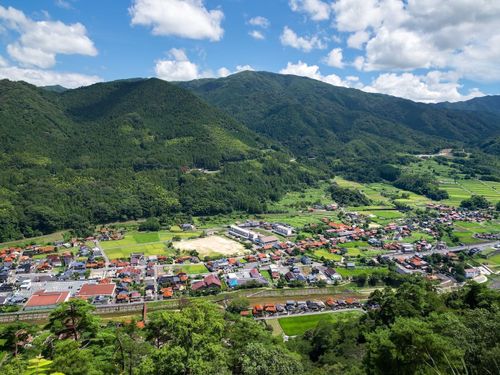 深い緑の⼭の⾕間に⾚い⽡の家並みが残る津和野町