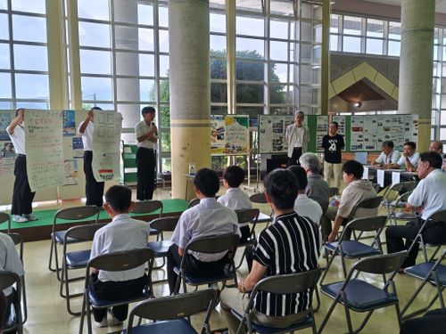 地元中学生の発表をサポートする㈱アイシン後藤氏と㈱ユニックの竹内氏